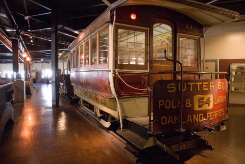 A vintage streetcar displayed in a museum, featuring red and white colors with "Sutter St. & Polk" signage.