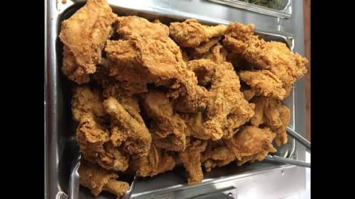 A large tray filled with golden-brown fried chicken pieces.