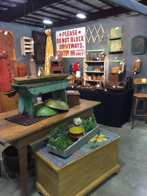 A rustic market display featuring vintage furniture, decor items, and a sign about parking restrictions.