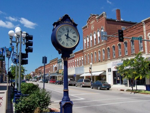A street view of Anamosa featuring a decorative clock and historic brick buildings under a clear blue sky.