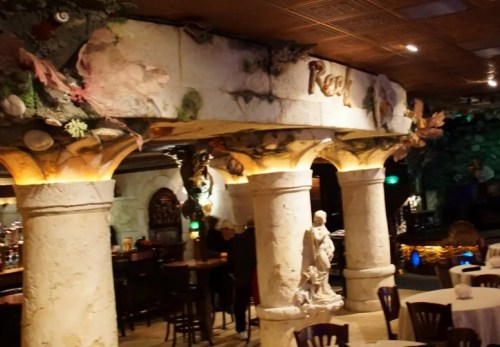 Interior of a themed restaurant featuring ornate columns, decorative shells, and a cozy dining atmosphere.