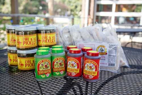 A table with jars of pickles and bottles of margarita mix in vibrant packaging.