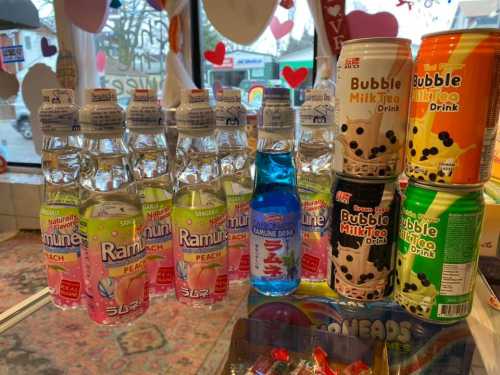 A display of various flavored Ramune bottles and colorful bubble tea cans on a counter.