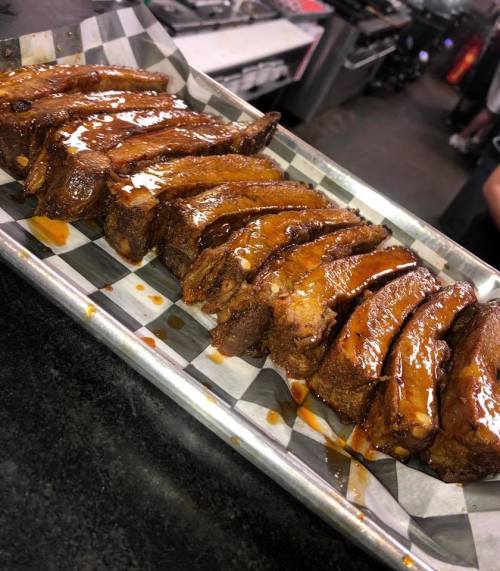 A platter of glazed ribs arranged neatly on a checkered paper-lined tray.