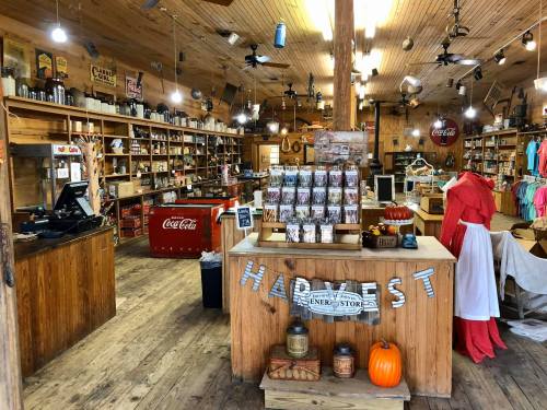 A rustic store interior with wooden shelves, vintage decor, and a display of seasonal items, including a pumpkin.