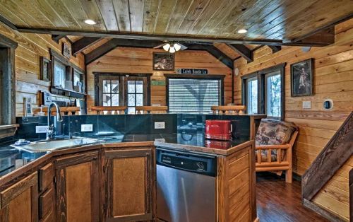 Cozy wooden kitchen with a bar, modern appliances, and rustic decor, featuring warm lighting and a comfortable seating area.