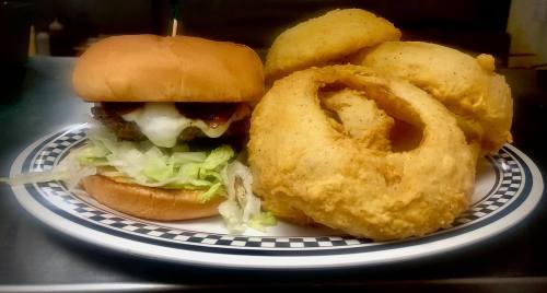 A plate featuring a burger with lettuce and cheese, accompanied by several golden, crispy onion rings.