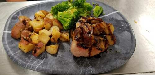 A plate with grilled chicken topped with pineapple, roasted potatoes, and steamed broccoli.