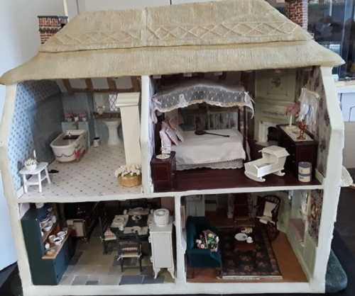 A detailed dollhouse interior featuring a living room, kitchen, bedroom, and bathroom with miniature furniture.