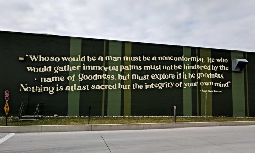 A mural featuring a quote about nonconformity and integrity by Ralph Waldo Emerson on a green wall.