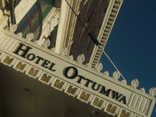 Sign for Hotel Ottumwa with ornate white detailing against a blue sky.