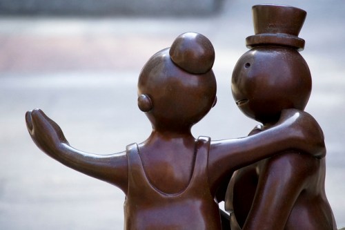 Two bronze sculptures of a couple embracing, with one wearing a top hat and the other in a dress.