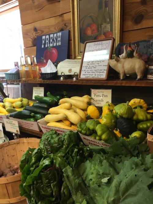 A vibrant display of fresh vegetables, including squash and greens, in a rustic market setting.