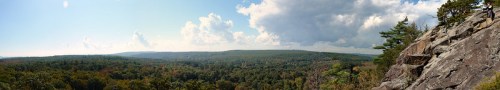 Panoramic view of a lush green landscape with rolling hills under a partly cloudy sky.