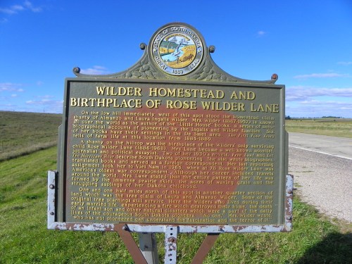 Historical marker for Wilder Homestead and birthplace of Rose Wilder Lane, set against a rural landscape.