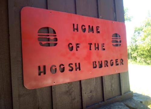 A red sign on a wooden wall reads "Home of the Hoosh Burger," featuring burger icons.