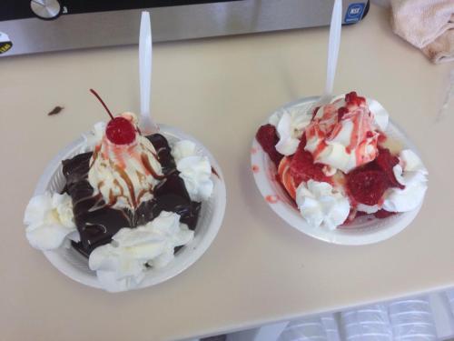 Two dessert bowls: one with a chocolate brownie topped with whipped cream and a cherry, the other with strawberries and cream.