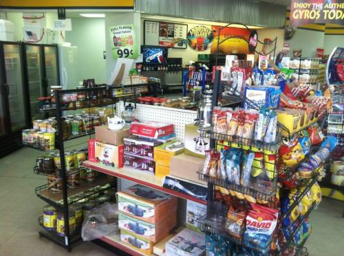 A convenience store interior featuring shelves of snacks, drinks, and various grocery items for sale.