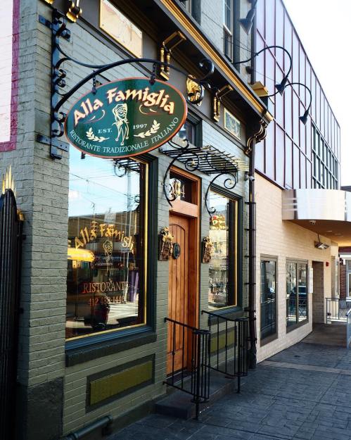 Exterior of "Alla Famiglia," a traditional Italian restaurant, featuring a wooden door and decorative signage.