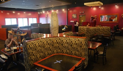 Interior of a restaurant featuring colorful decor, booth seating, and patrons enjoying their meals.