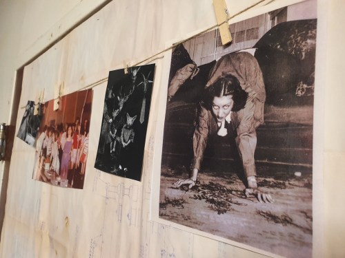A wall display featuring various black-and-white photos, including a woman in a creepy pose and a group of people.