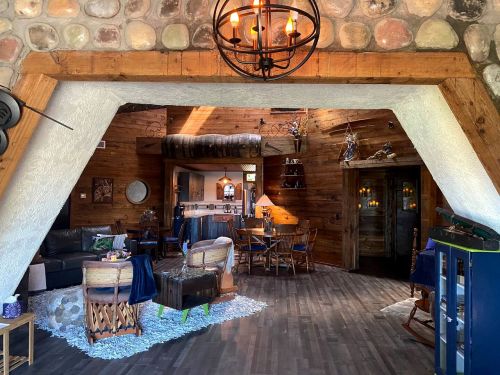 Cozy interior of a rustic cabin featuring wooden beams, stone walls, and a warm, inviting living space.
