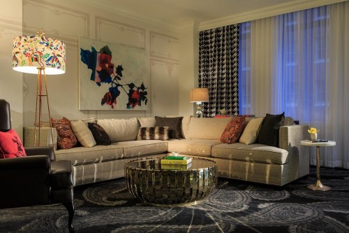 A stylish living room featuring a large sectional sofa, decorative pillows, a coffee table, and artistic lighting.