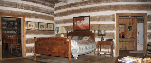 Cozy log cabin interior featuring a bed, wooden furniture, and rustic decor with framed pictures on the walls.