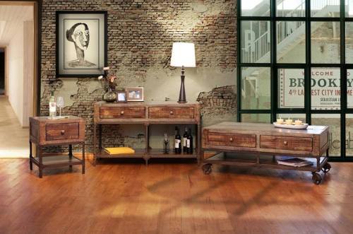 A stylish living room with rustic furniture, a lamp, and a brick wall backdrop, featuring a framed artwork.