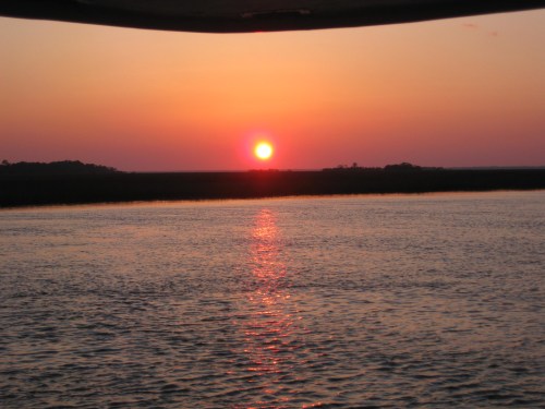 A serene sunset over calm waters, with vibrant orange and pink hues reflecting on the surface.