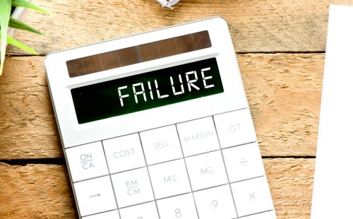 A calculator displaying the word "FAILURE" on its screen, placed on a wooden surface.