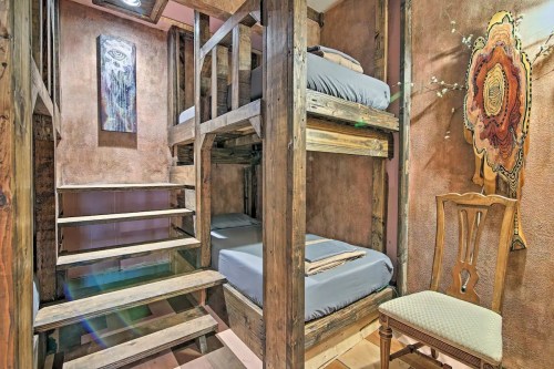 Cozy interior with wooden bunk beds, a staircase, and a decorative wall art piece. Warm, rustic ambiance.