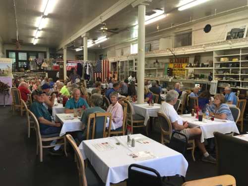 A busy restaurant filled with patrons seated at tables, chatting and enjoying their meals in a casual setting.