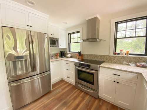 Modern kitchen with stainless steel appliances, granite countertops, and white cabinetry, featuring a cozy, bright atmosphere.