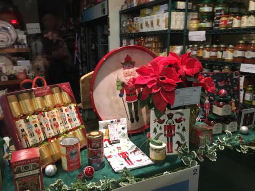 A festive display featuring nutcracker decorations, poinsettias, and holiday-themed items in a shop window.
