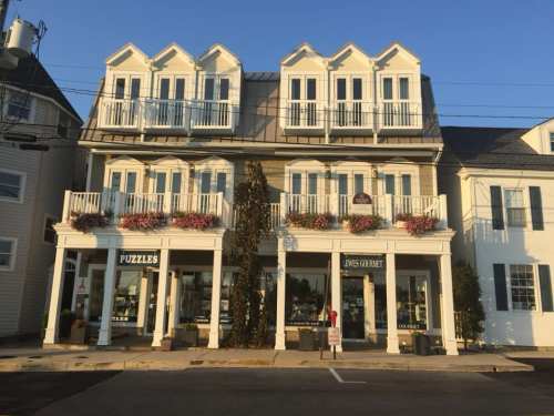 A charming building with multiple balconies, featuring shops labeled "PUZZLES" and "JONES CRAFTS" in a sunny setting.