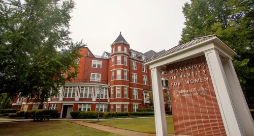 Historic building of Mississippi University for Women, featuring red brick architecture and a welcoming entrance sign.