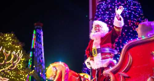 Santa Claus waves from his sleigh, surrounded by colorful holiday lights and decorations.