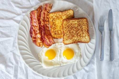 A plate with two sunny-side-up eggs, crispy bacon, and two slices of golden-brown French toast.