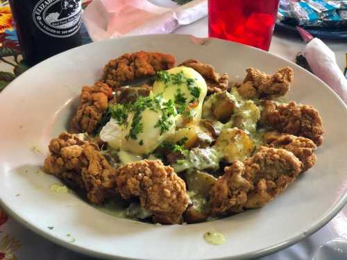 A plate of fried chicken topped with poached eggs and green sauce, garnished with parsley.