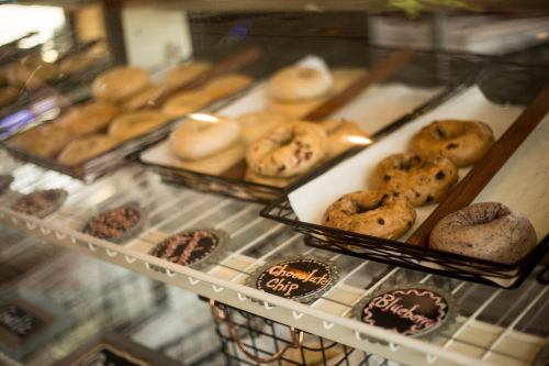 A display case filled with various bagels, including chocolate chip and blueberry, on wooden trays.