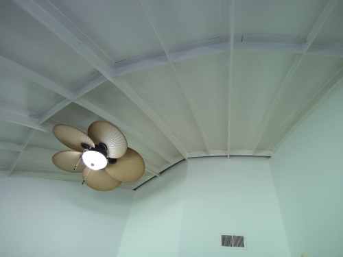 Ceiling with a light-colored finish and a large ceiling fan with five blades.