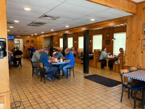 A cozy restaurant interior with wooden decor, featuring diners at tables and booths enjoying their meals.