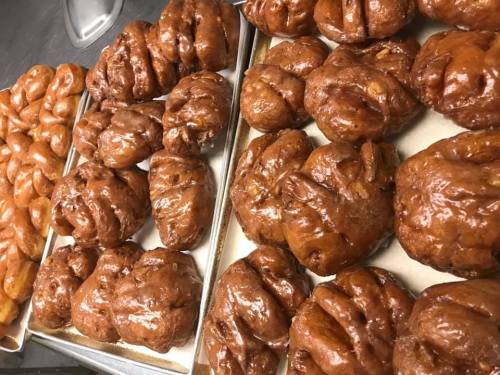 Trays of freshly baked, glazed pastries in various shapes and sizes, including twisted and knotted forms.