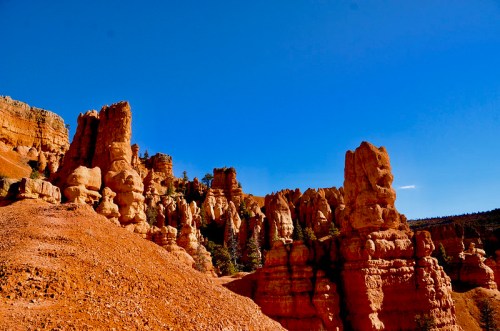 Rock formations in a desert landscape under a clear blue sky, showcasing vibrant orange and red hues.