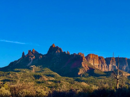 Majestic mountain range under a clear blue sky, showcasing rugged peaks and vibrant rock formations.