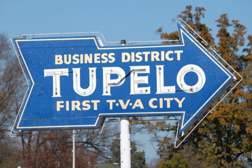 Blue sign pointing right, reading "Tupelo, Business District, First TVA City."