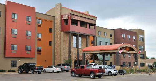 A colorful hotel building with multiple stories and a welcoming entrance, surrounded by parked cars.