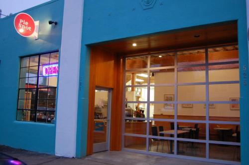 Exterior of a bright blue building with a sign reading "Pie Spot" and an open door, inviting customers inside.
