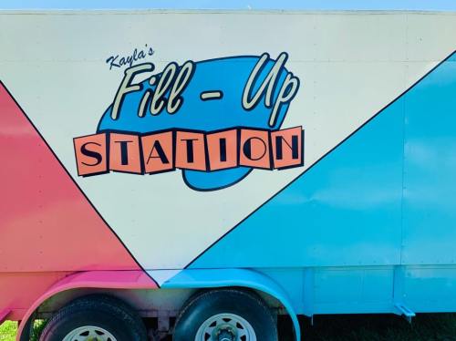 Colorful food truck with the text "Kayla's Fill-Up Station" in a playful font on a blue and pink background.